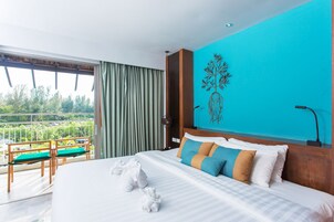 Habitación de hotel con una cama grande, vistas al exterior, un balcón con sillas y un adorno en la pared.