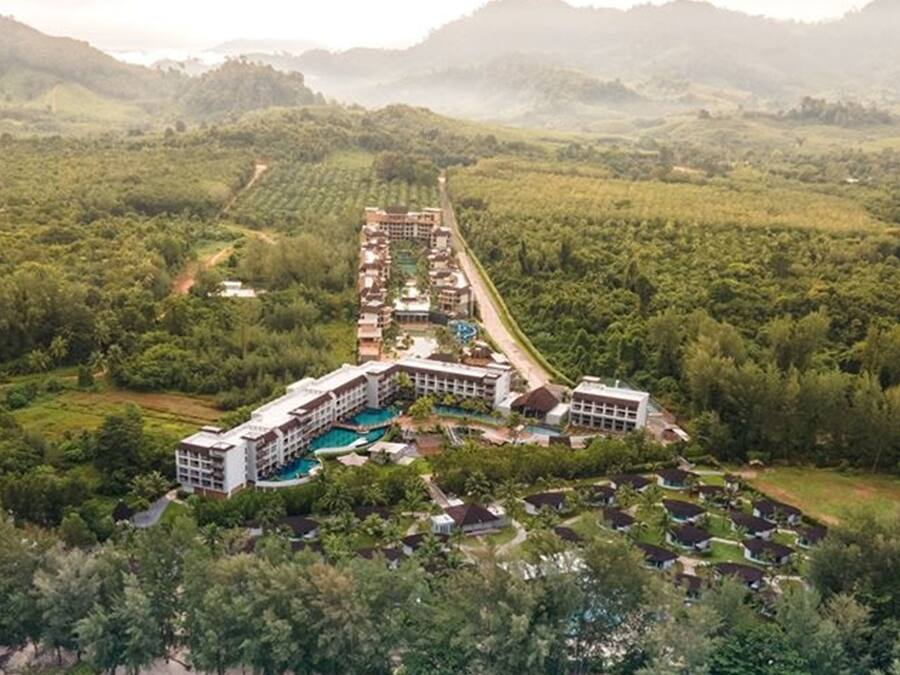 Un resort con un edificio central, varias habitaciones de huéspedes y una piscina.