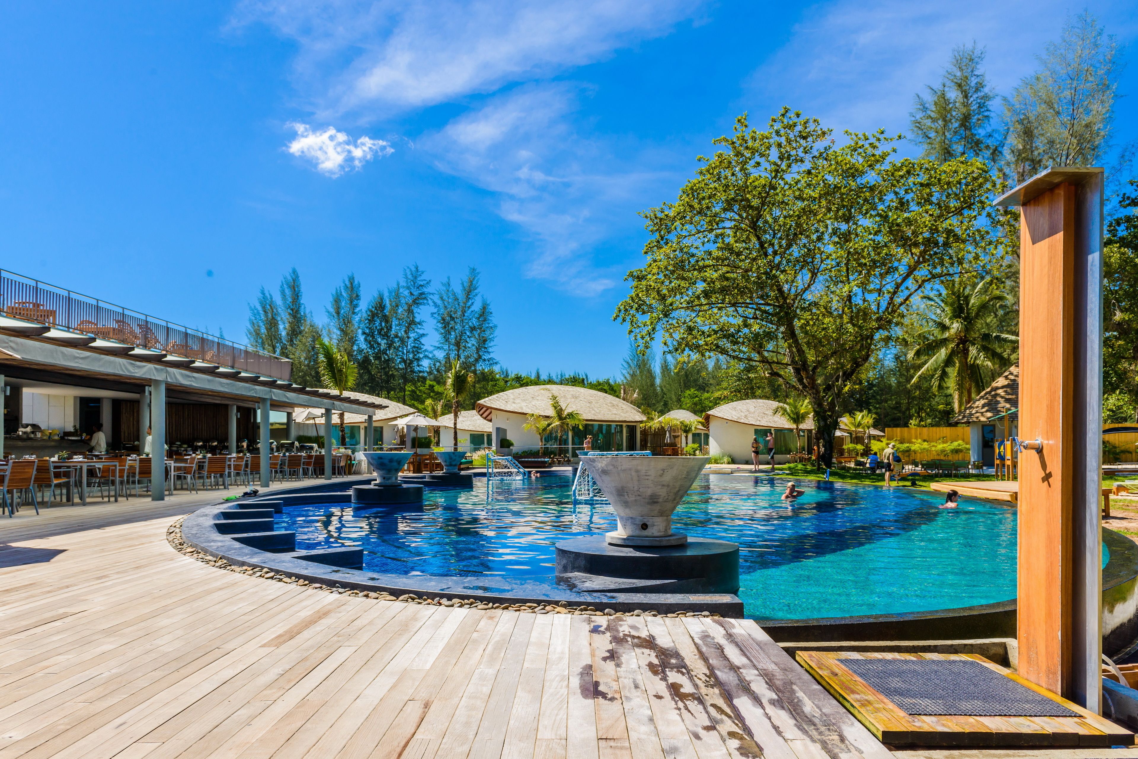 Ein Poolbereich mit Holzterrasse, Liegestühlen und Sonnenschirmen.