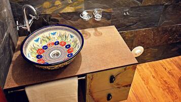 Un baño con un espejo redondo, un lavabo con diseño floral y un mueble de madera.
