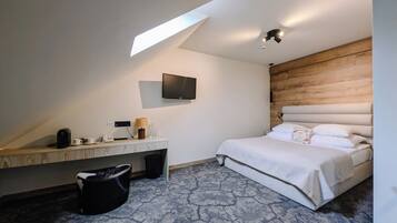 A hotel room with a bed, a desk with a lamp, a TV, and a large window.