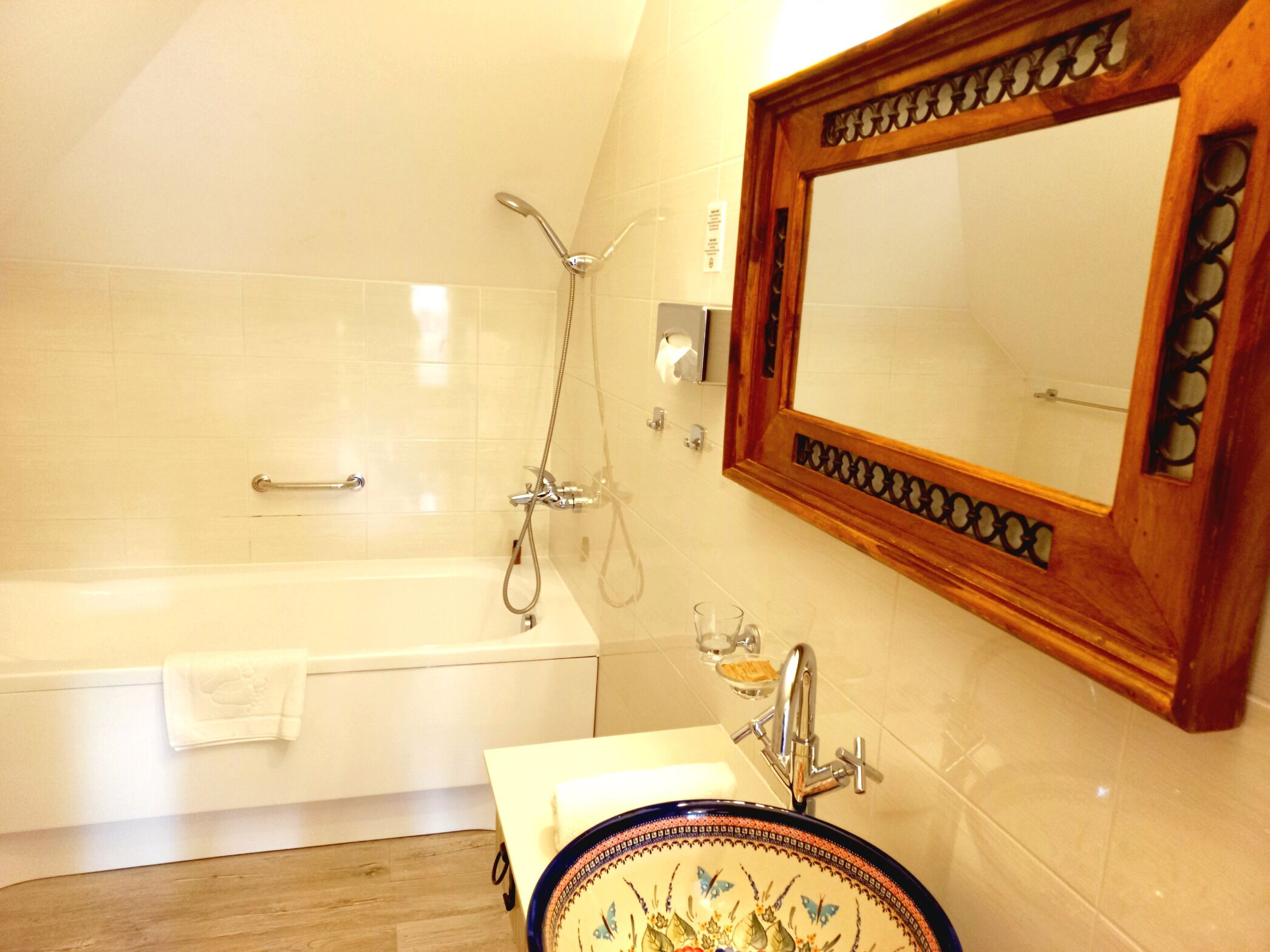 A bathroom with a bathtub, a sink with a decorative basin, and a mirror with a wooden frame.