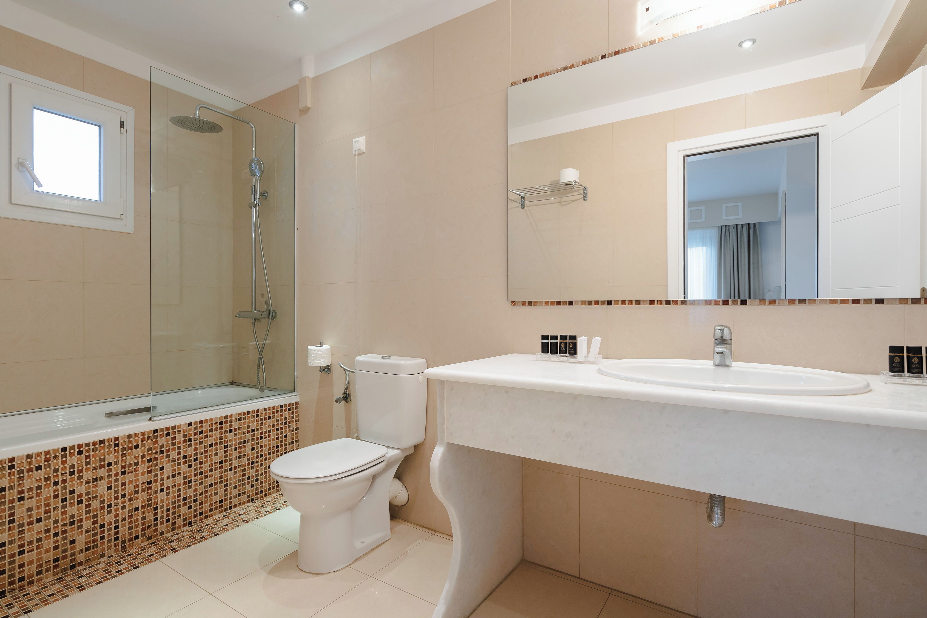 A modern bathroom with a glass-enclosed shower, a white toilet, and a large mirror above a white sink.