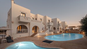 A modern villa with a swimming pool, multiple balconies, and a stone facade. - Mitos Suites (Naxos)
