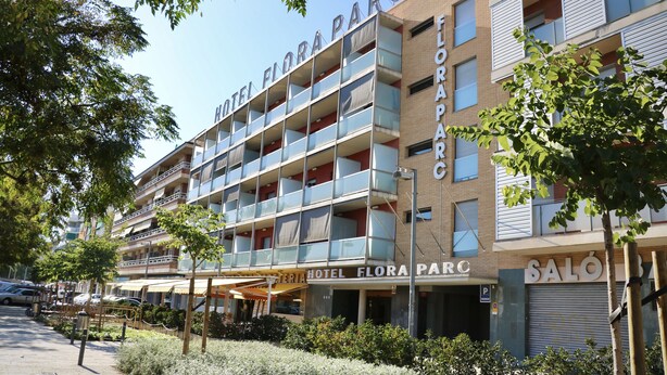 A multi-story hotel with balconies, a parking area, and a visible entrance. - Hotel Flora Parc (Castelldefels)