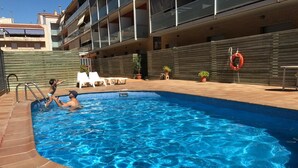 A swimming pool with tiled edges, a lifebuoy, and lounge chairs. - Hotel Flora Parc (Castelldefels)