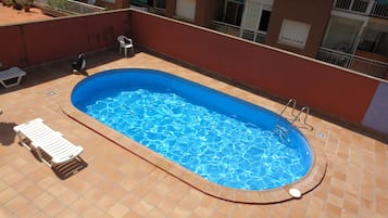 Piscina a l'aire lliure de temporada, para-sols i gandules