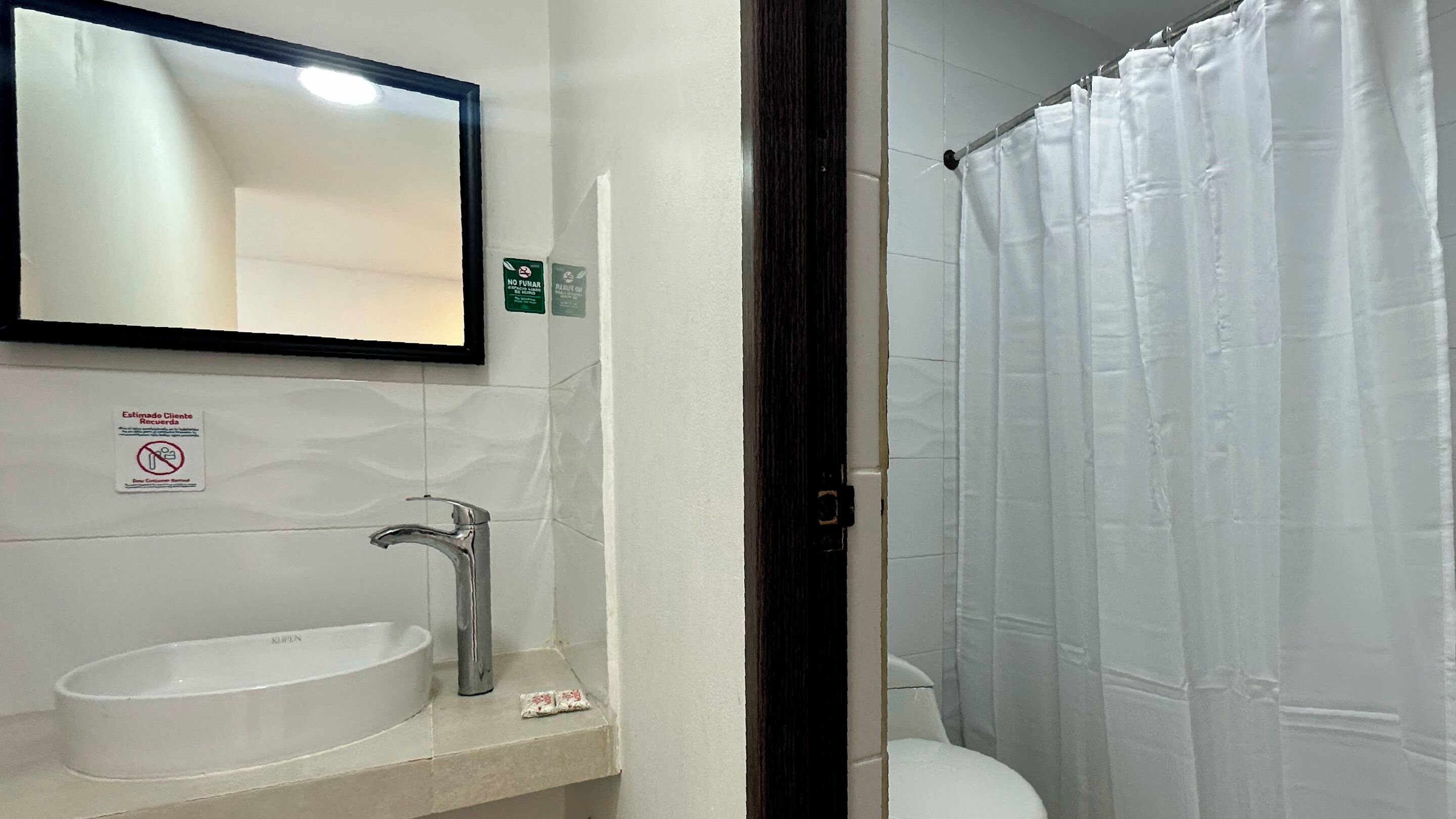 Ein Badezimmer mit weißem Waschbecken, einem Spiegel und einer Duschvorhang.