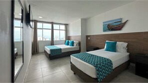 Ein Hotelzimmer mit zwei Betten, einem großen Fenster mit Stadtblick, einem Wandfernseher und einem Bild an der Wand.