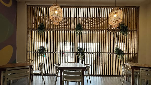 A dining area with a wooden slatted partition, hanging wicker light fixtures, and a central table with chairs. - Hotel Tower by On vacation (San Andrés)