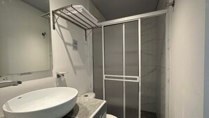 A bathroom with a white sink, a towel rack, a toilet, and a shower area with a glass door. - Hotel Tower by On vacation (San Andrés)