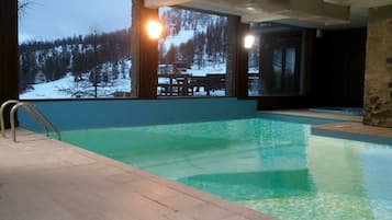 Una piscina con vistas a un paisaje nevado y una terraza de madera.