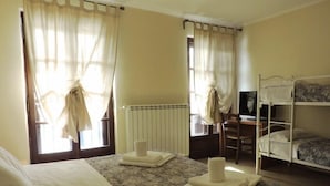 A hotel room with two beds, a desk, a chair, and a radiator. - Baita della Luna (Cesana Torinese)