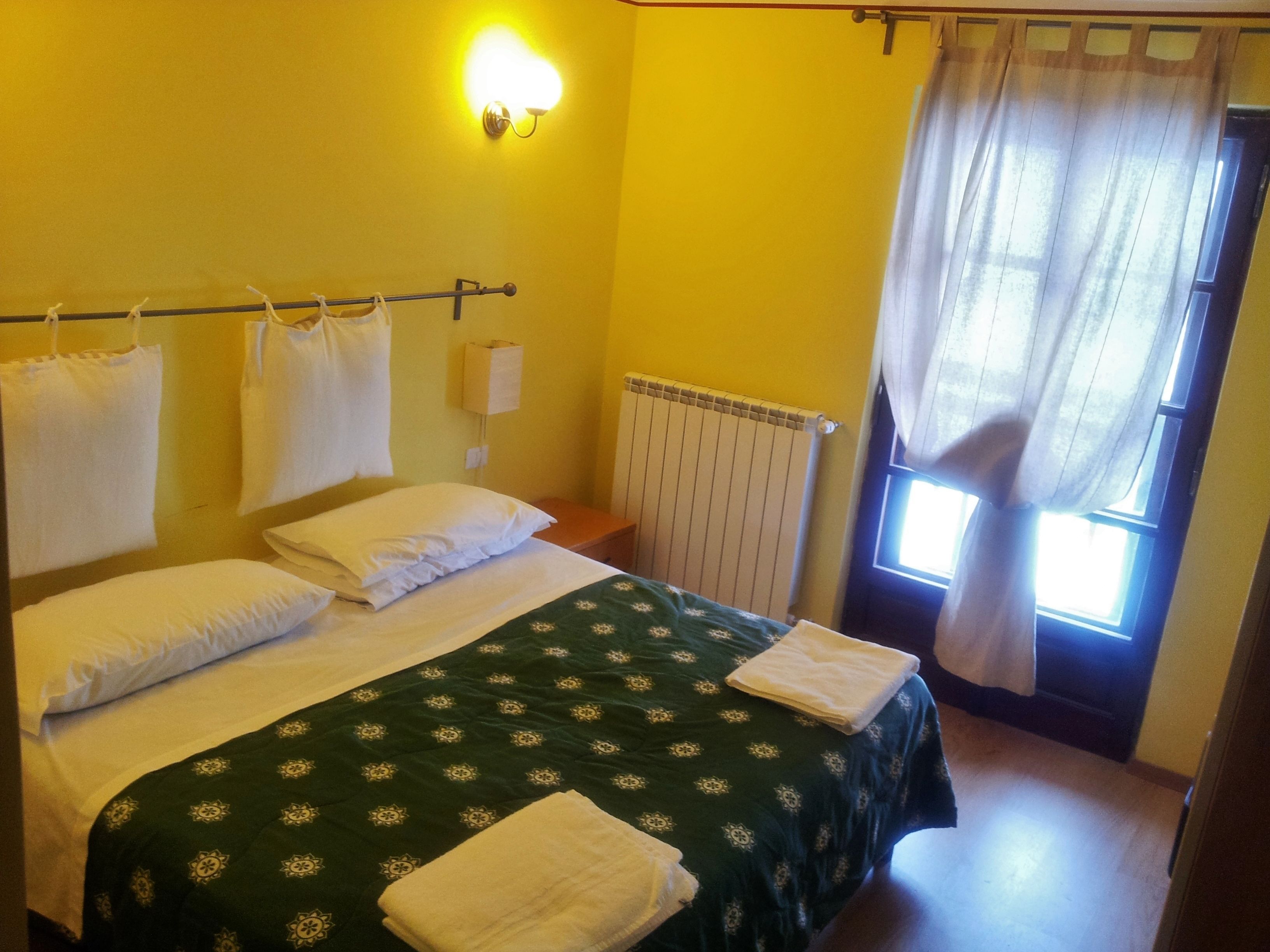 A room with a bed, a radiator, and a window with curtains.