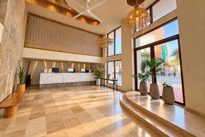 A hotel lobby with a reception desk, seating area, and large windows offering a view of the street. -  Hotel Toné by On vacation (San Andrés)