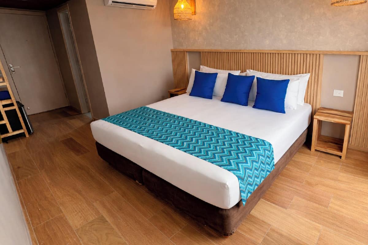 A hotel room with a large bed, wooden headboard, and a blue and white patterned bedspread.