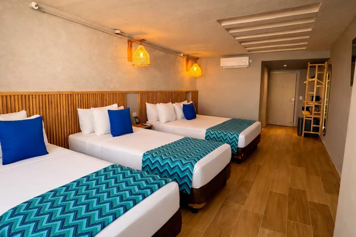 A hotel room with three beds, wooden headboards, and a wooden floor.