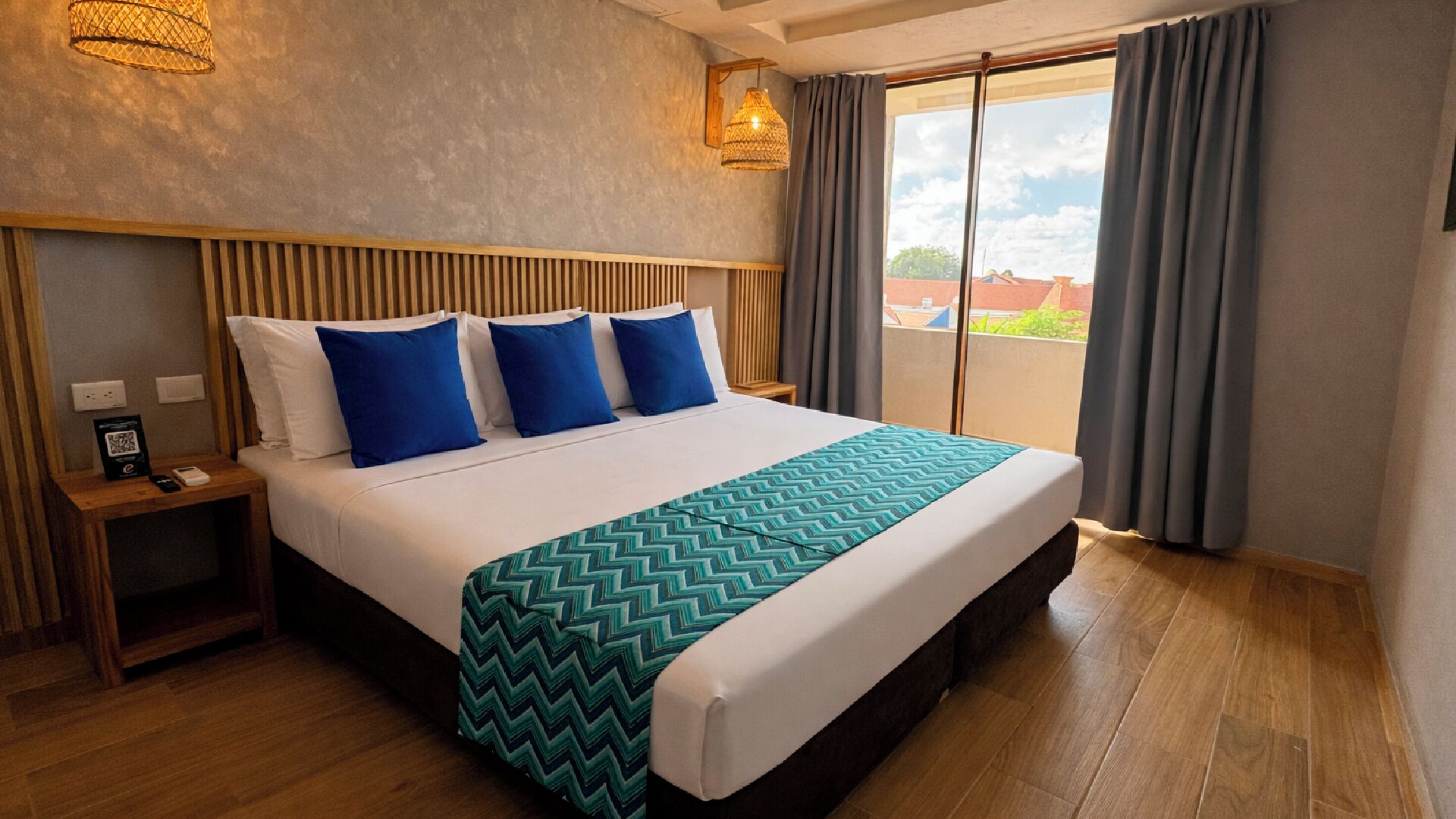 Habitación de hotel con una cama grande, cabecera de madera y vista a la ciudad desde la ventana.