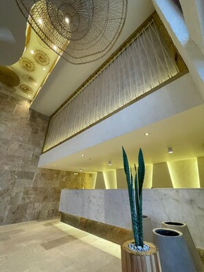 A lobby with a high ceiling, stone walls, and a reception desk. -  Hotel Toné by On vacation (San Andrés)