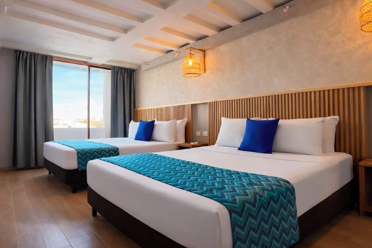 A hotel room with two beds, a large window, and a wooden ceiling.