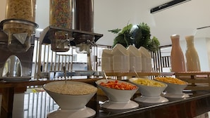 A buffet with various food options including cereal, pasta, and vegetables.