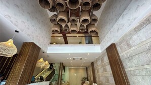 Un interior moderno con una escalera central, un colgante de luz y vistas al piso superior.
