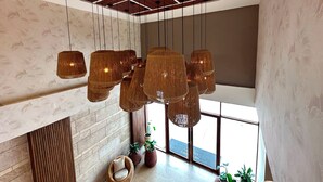 Un interior moderno con techo alto, ventanas grandes y una lámpara colgante en el centro.
