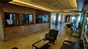 Un vestíbulo amplio con mostrador de recepción, zona de estar y vistas al comedor.