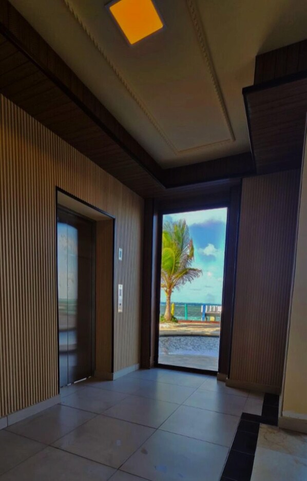 A hotel lobby with a tiled floor, a wooden panel wall, and a door leading outside. - Hotel Lord Pierre (San Andrés)