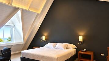 Une chambre avec un plafond en pente, un lit, des tables de chevet et une chaise.