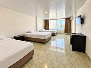 A hotel room with three beds, a desk, and a television. - Hotel Lord Pierre (San Andrés)
