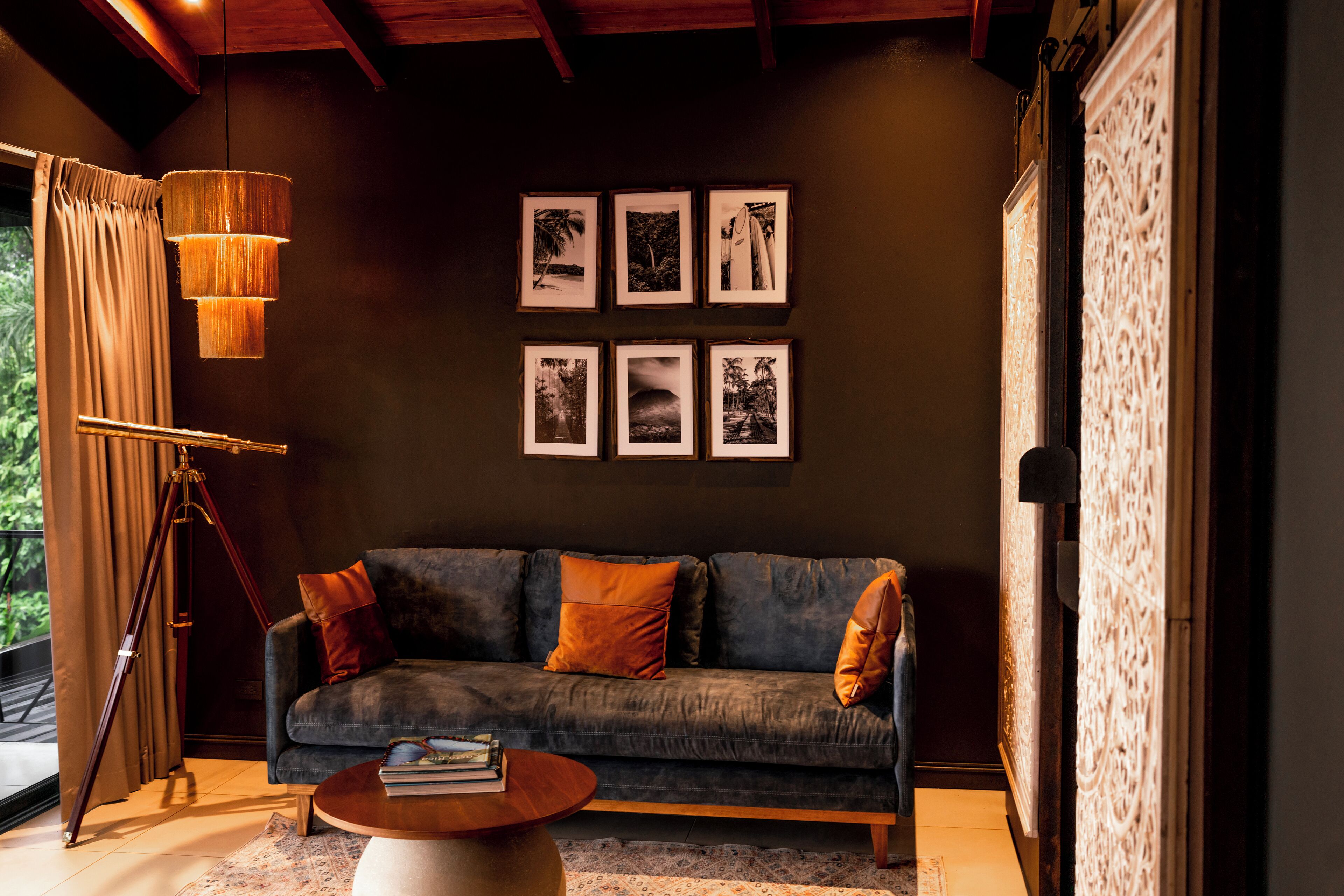 A modern living room with a dark wall, a blue sofa, and a wooden floor lamp.