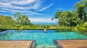 Una piscina al aire libre, sombrillas, sillones reclinables de piscina