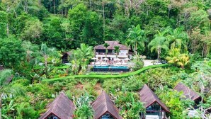 Un complexe hôtelier comprenant plusieurs bâtiments de style bungalow, une piscine et une végétation tropicale luxuriante.