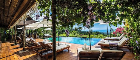 Una piscina al aire libre, sombrillas, sillones reclinables de piscina