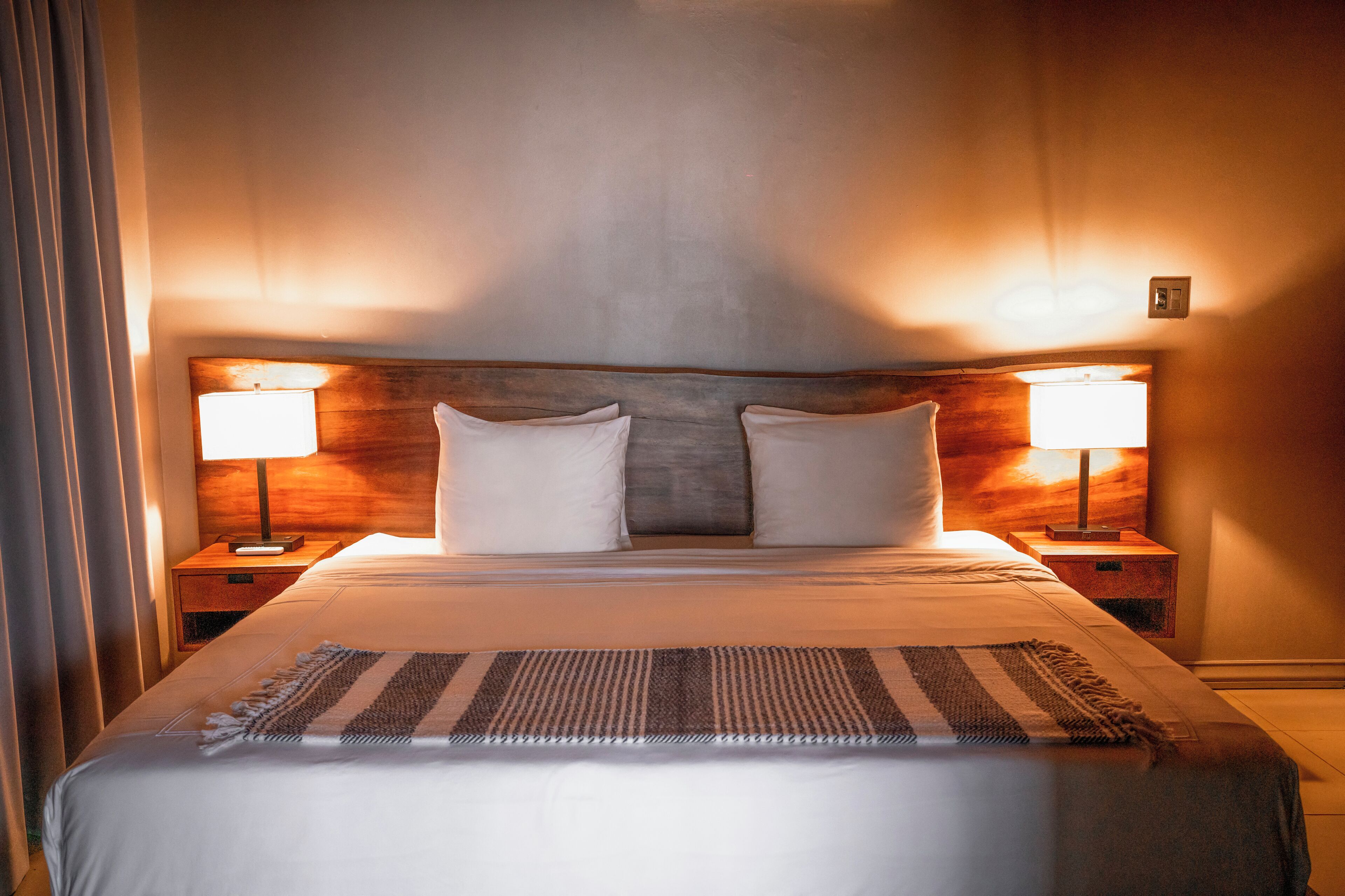 Una habitación de hotel con una cama grande, dos lámparas de noche y un cabecero de madera.