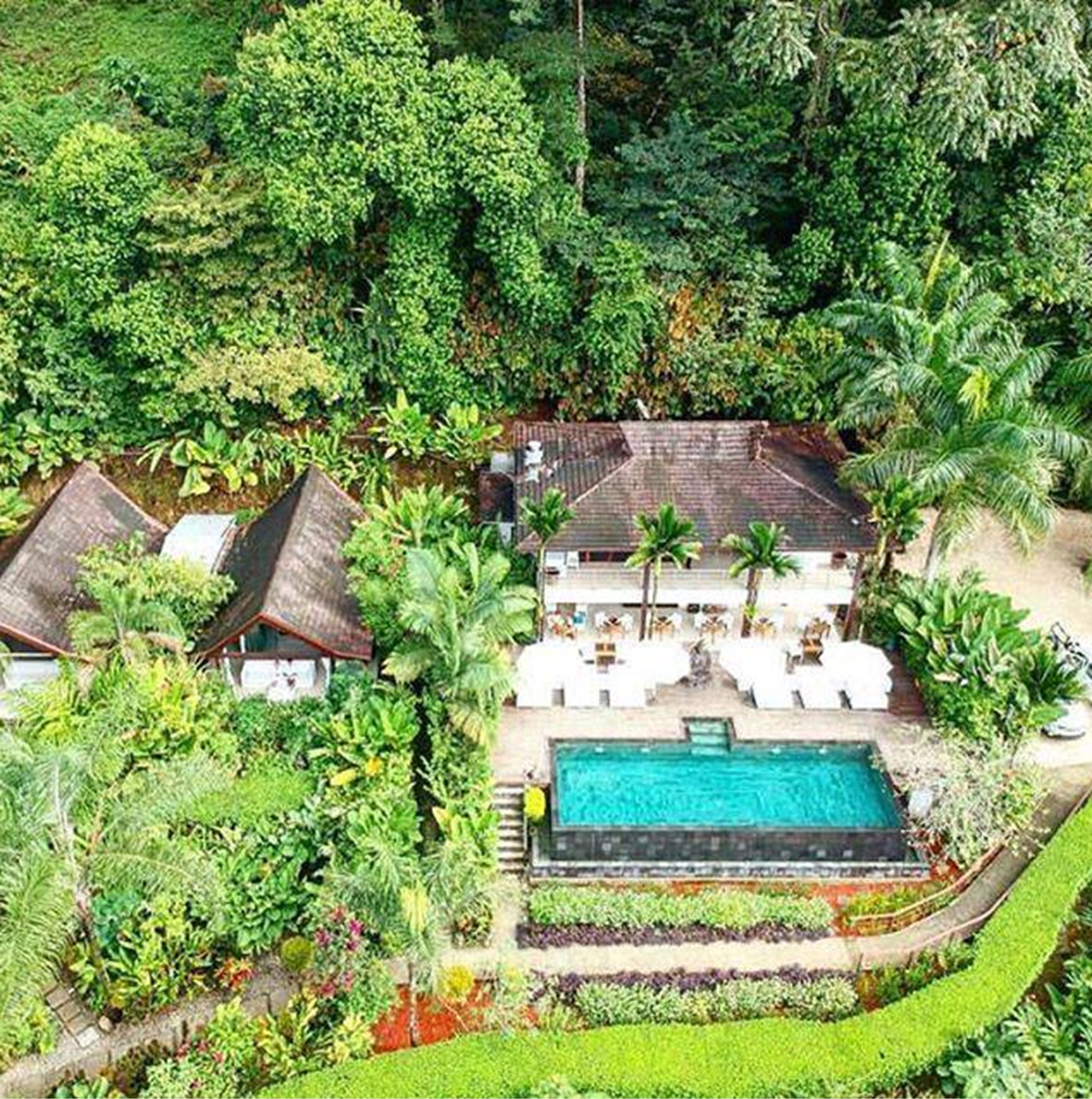 An aerial view of a resort with multiple buildings, a swimming pool, and lush greenery.