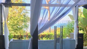 Un espace extérieur moderne et aménagé, à l’abri du vent, avec une cloison en verre, un banc et un luminaire suspendu.