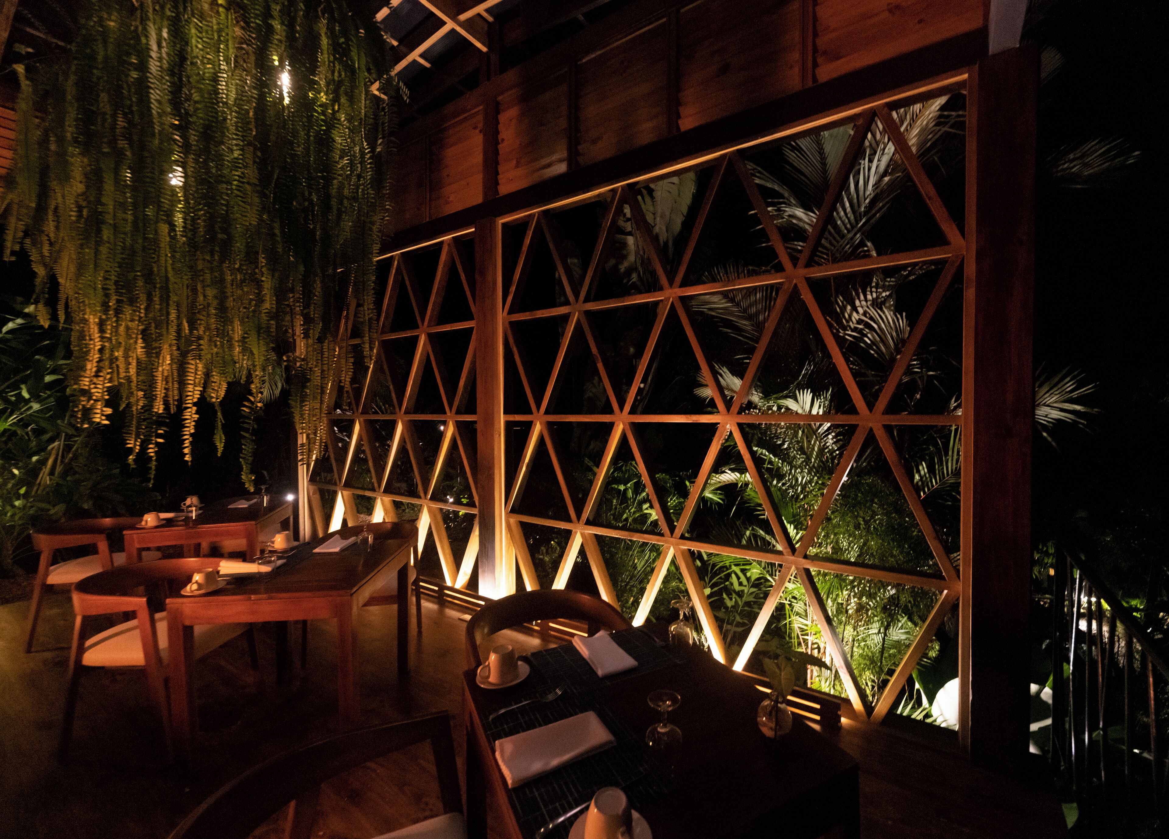An indoor dining area with wooden furniture and a large window with a geometric pattern.