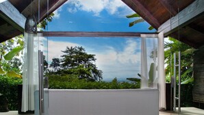 Une pièce dotée d’une grande fenêtre en verre donnant sur un arbre et le ciel.