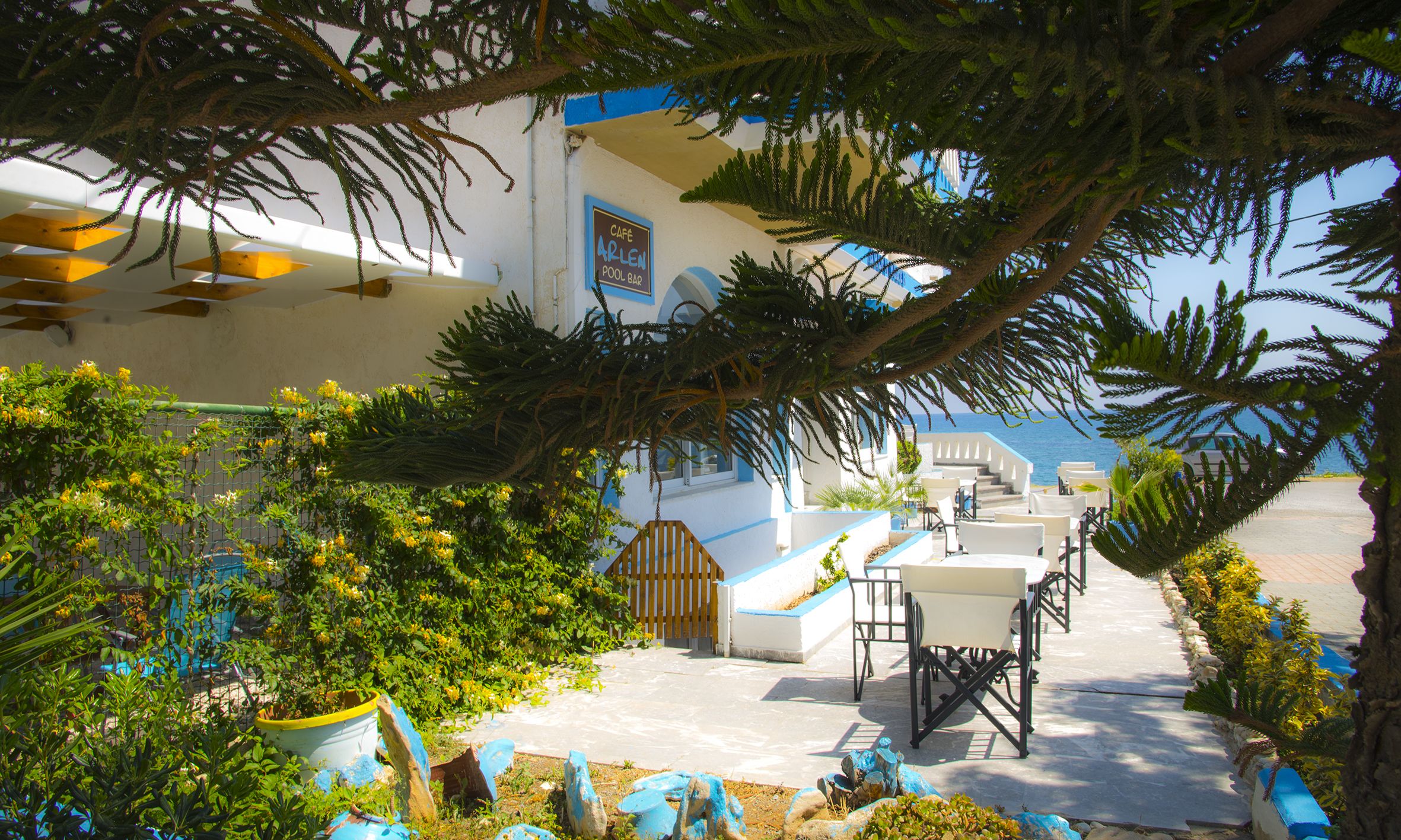 A coastal building with a pool area, outdoor seating, and a view of the sea.