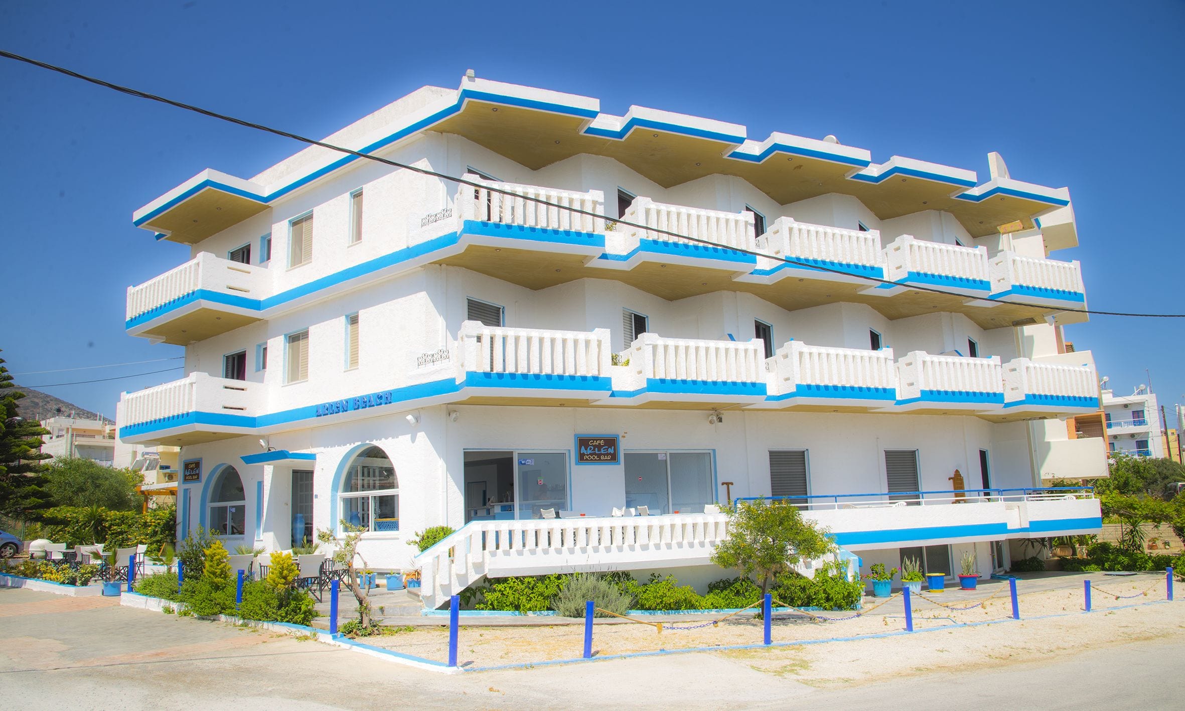 Un hotel de varios pisos con balcones, piscina y cafetería.