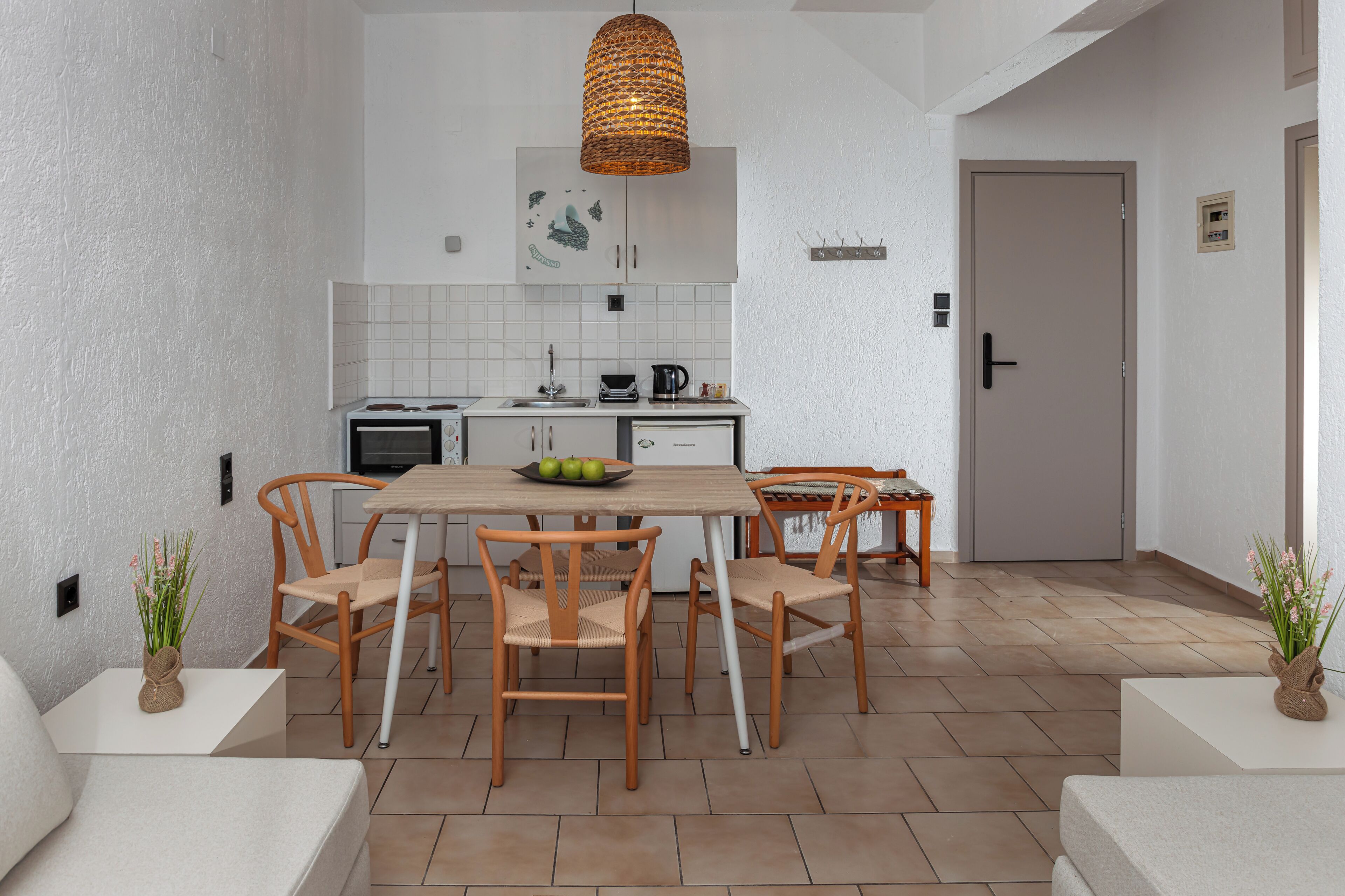 Una cocina moderna con armarios blancos, una mesa de comedor con sillas, una lámpara colgante y un salpicadero de azulejos.