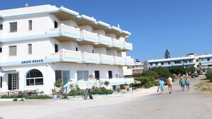 Un hôtel à plusieurs étages, doté de balcons et offrant une vue sur la plage, avec une enseigne indiquant « AELEN BEACH ».