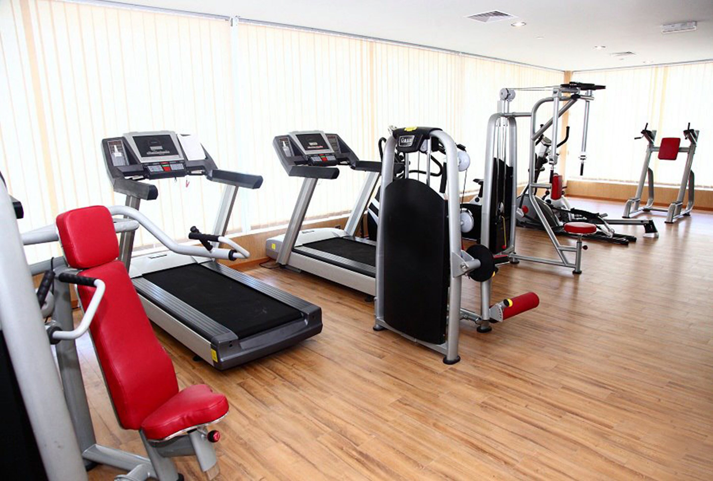 A gym with treadmills, weight machines, and red exercise chairs.