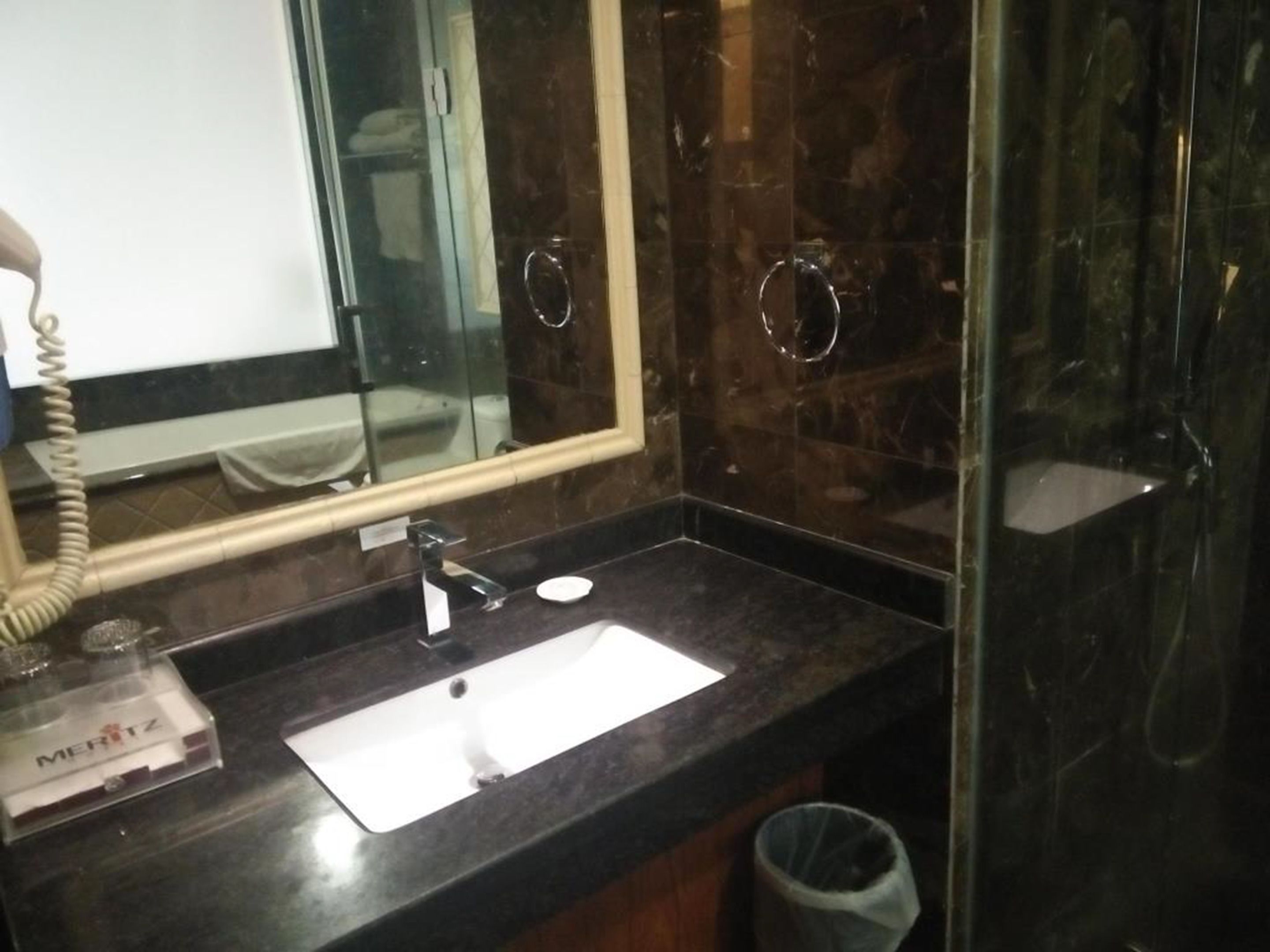 A bathroom with a marble sink, a mirror, and a glass shower enclosure.