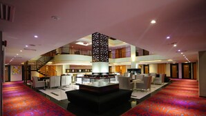 A spacious lobby with a central seating area, a staircase, and a decorative pillar. - Meritz Hotel (Miri)