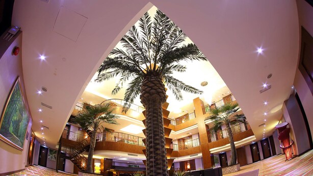 A spacious atrium with a central palm tree, multiple floors, and a patterned floor. - Meritz Hotel (Miri)