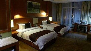 A hotel room with two beds, a desk, and a chair.
