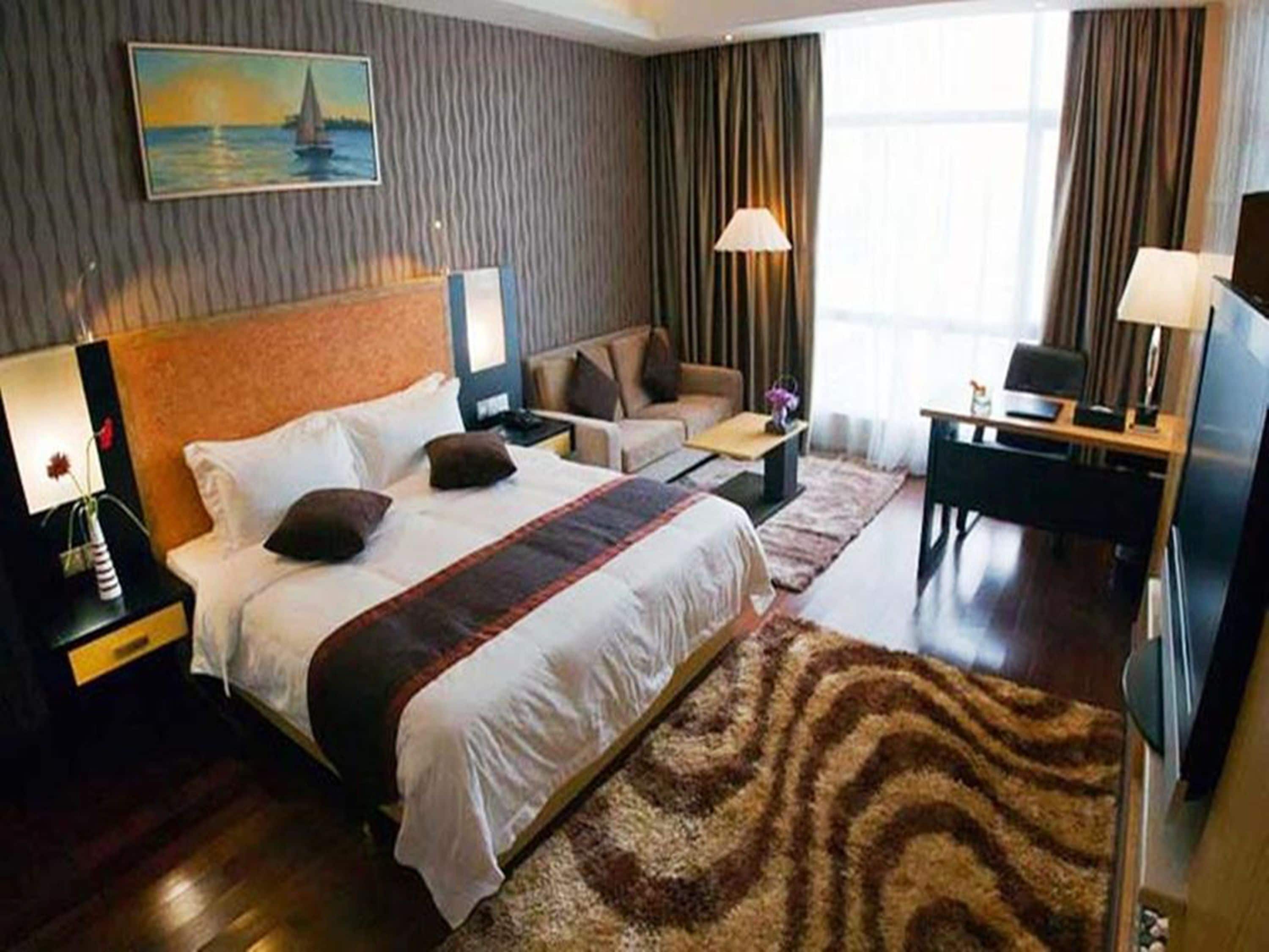 Ein Hotelzimmer mit einem großen Bett, einer Couch, einem Schreibtisch und einem Fernseher.